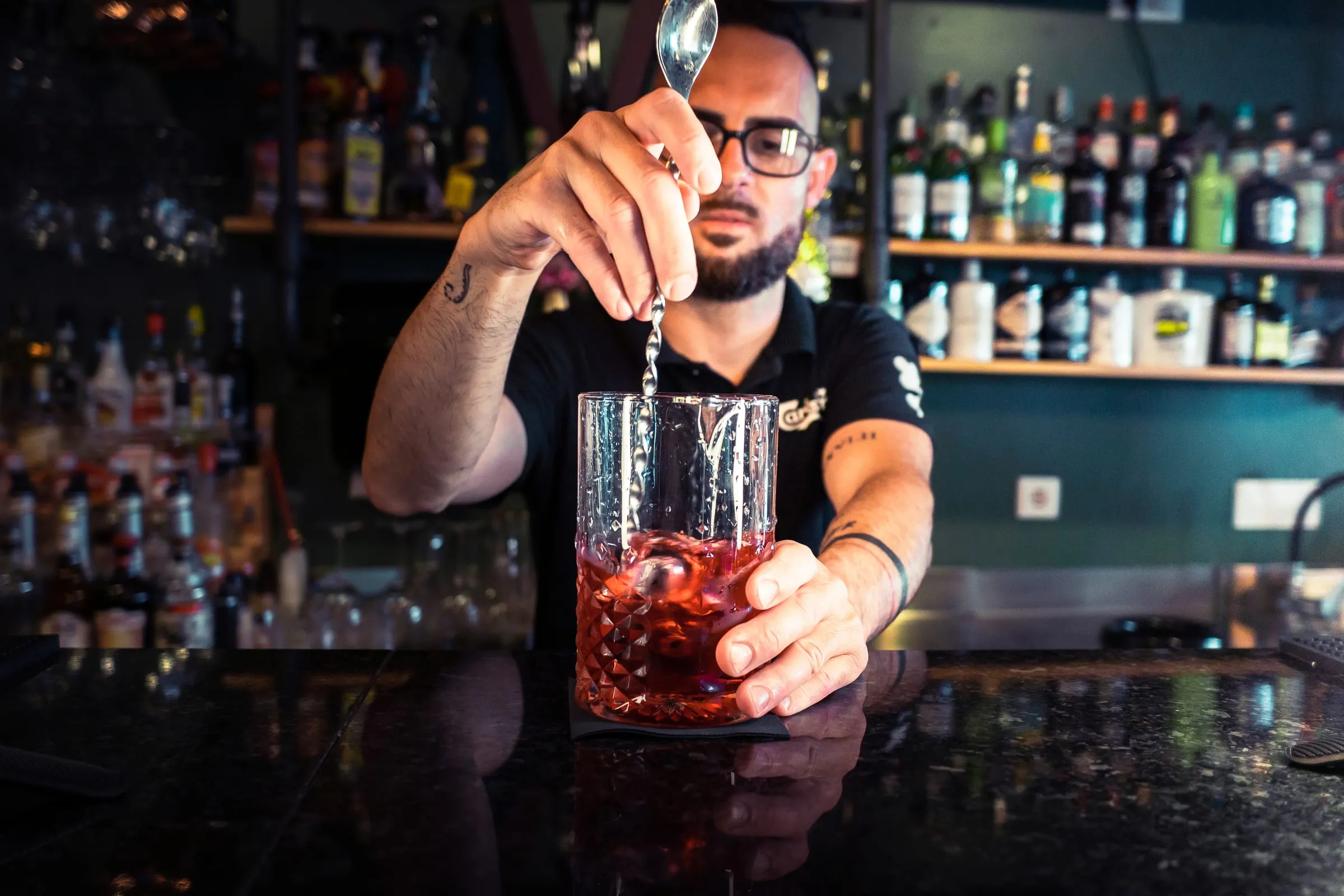Barman mexe um cocktail num copo misturador.