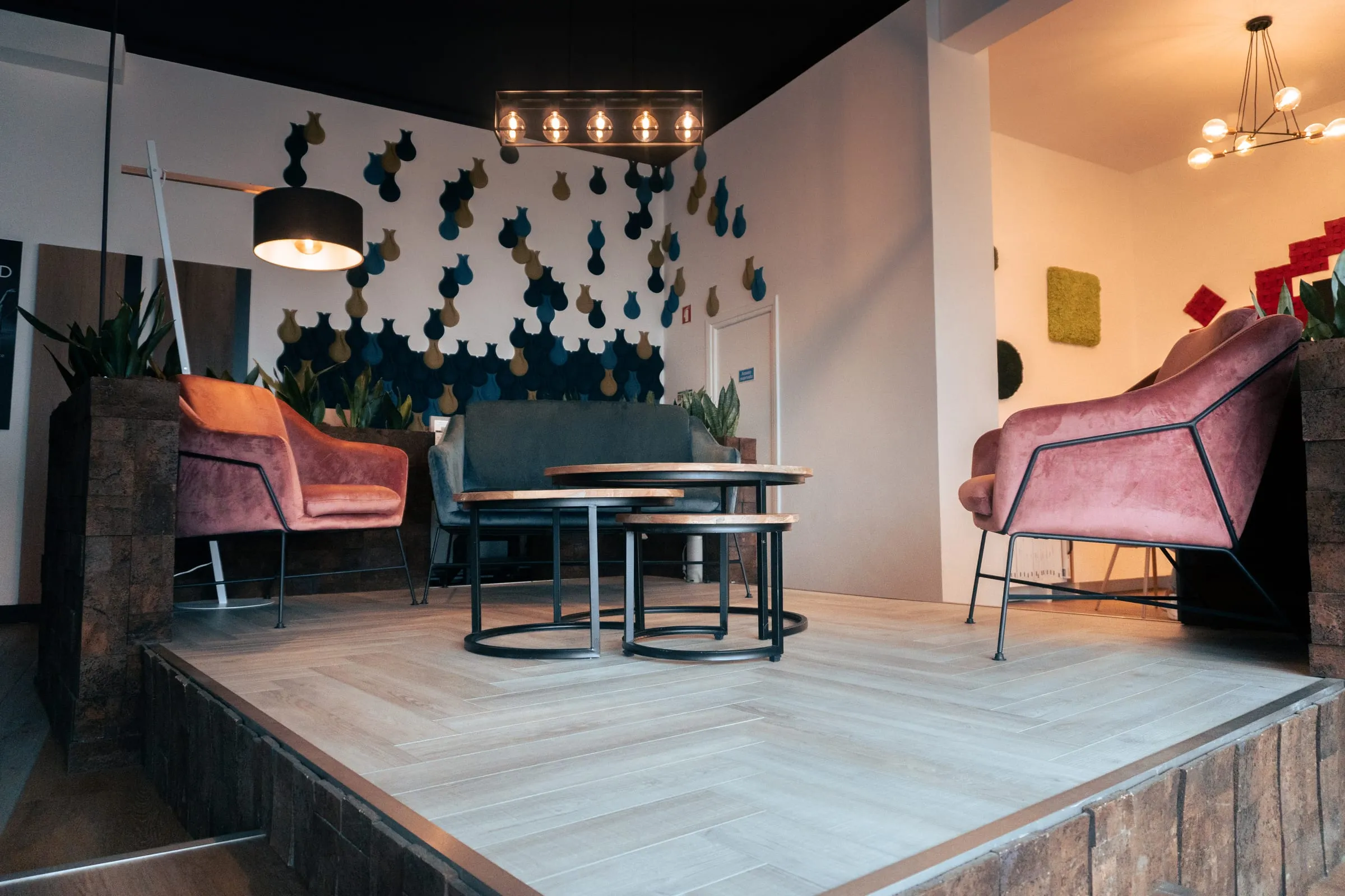 Zona de estar do showroom com sofás, mesa e candeeiros suspensos.